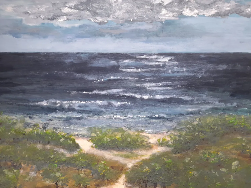 A grey bank of cloud over a deep blue sea with white breakers; in the foreground green dunes, through which a pale sandy path forks towards the viewer.
