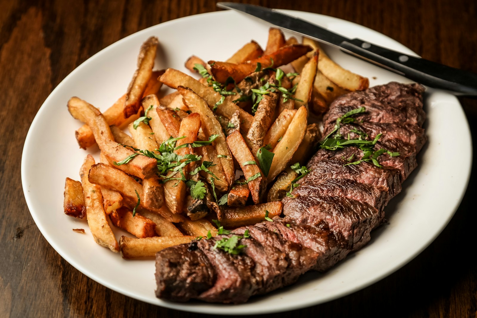 Zwiebelrostbraten mit Beilage auf dunklem Holztisch