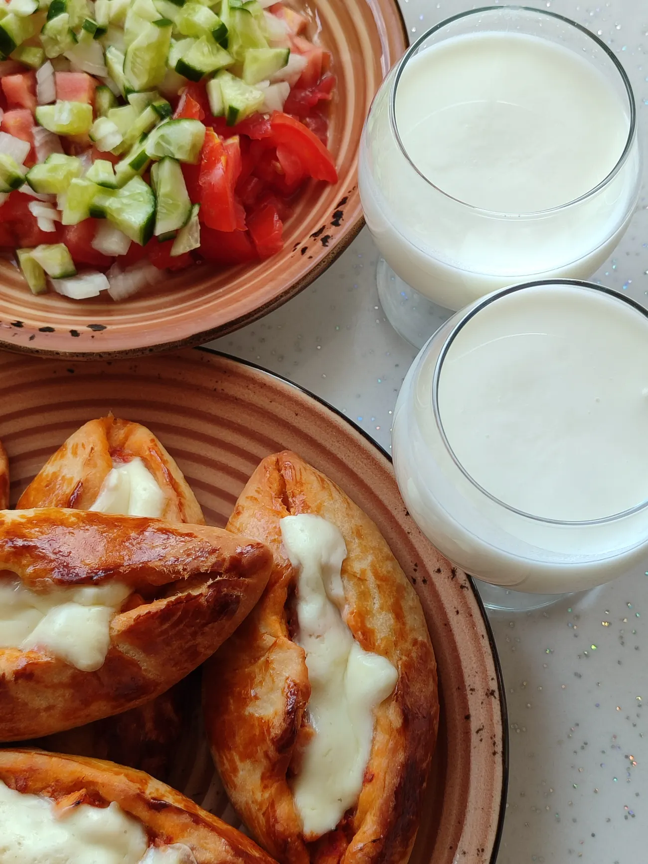 Zwei Gläser Ayran mit Käse-Pide und gehacktem Salat von oben