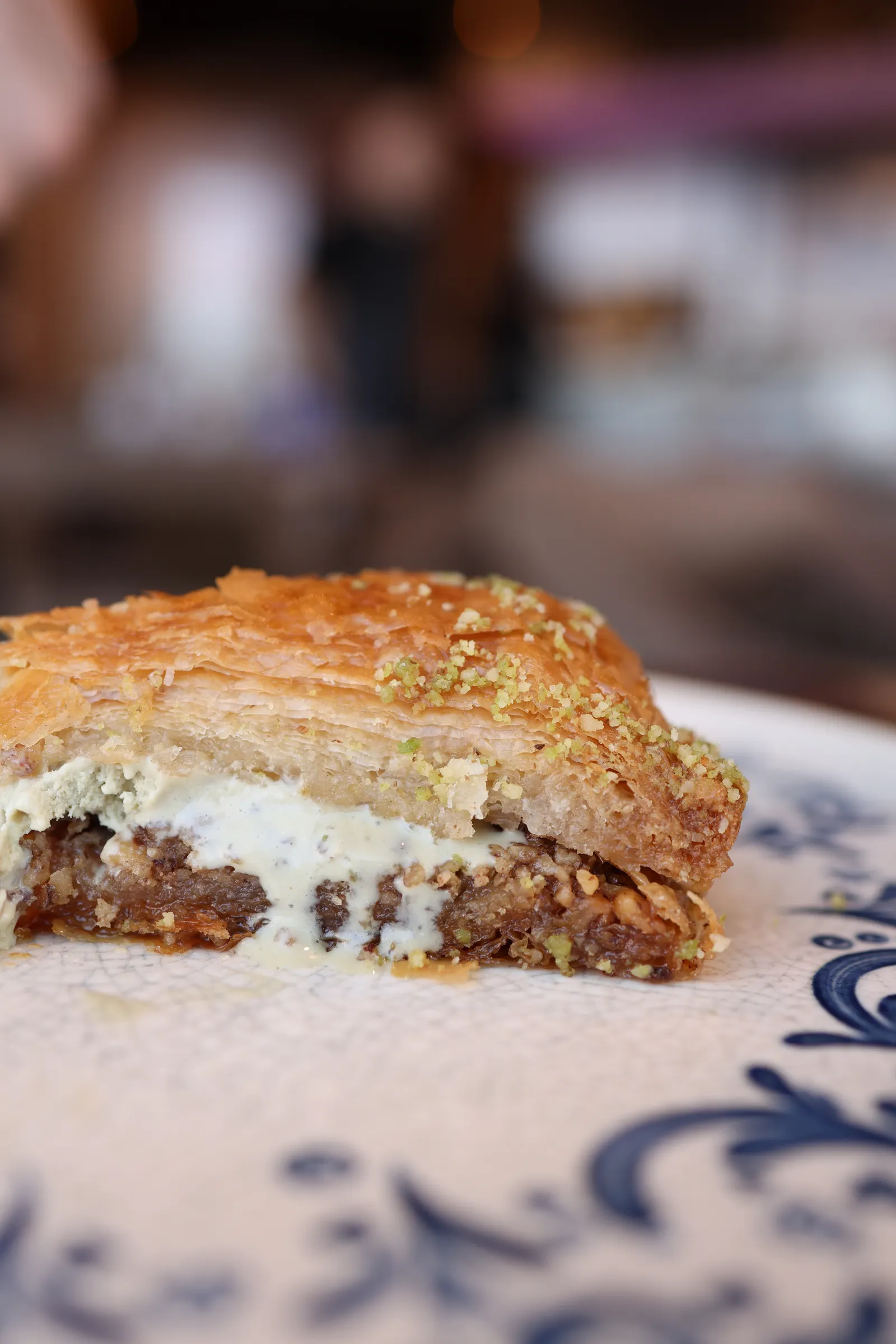 Baklava-Stück mit Pistazienstaub und schmelzender Creme auf einem Teller
