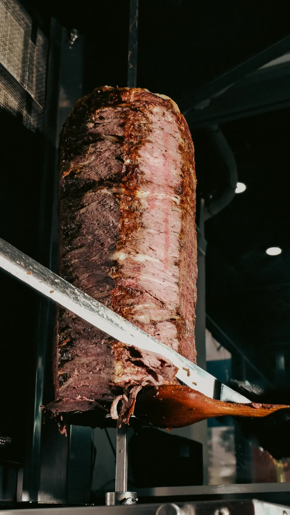 Mit dem langen Messer wird Fleisch hauchdünn vom Spieß geschnitten