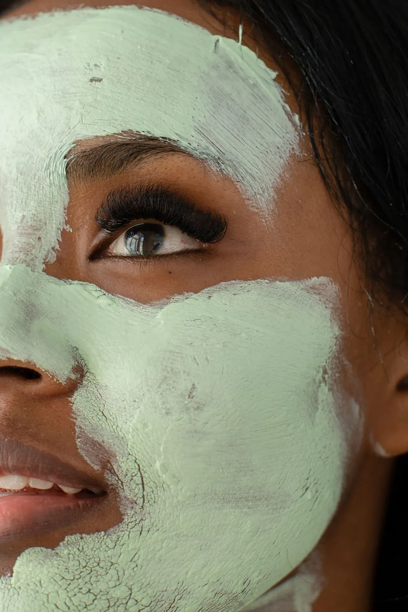 Gesicht mit einer grünen Maske, die auf Wange und Stirn antrocknet