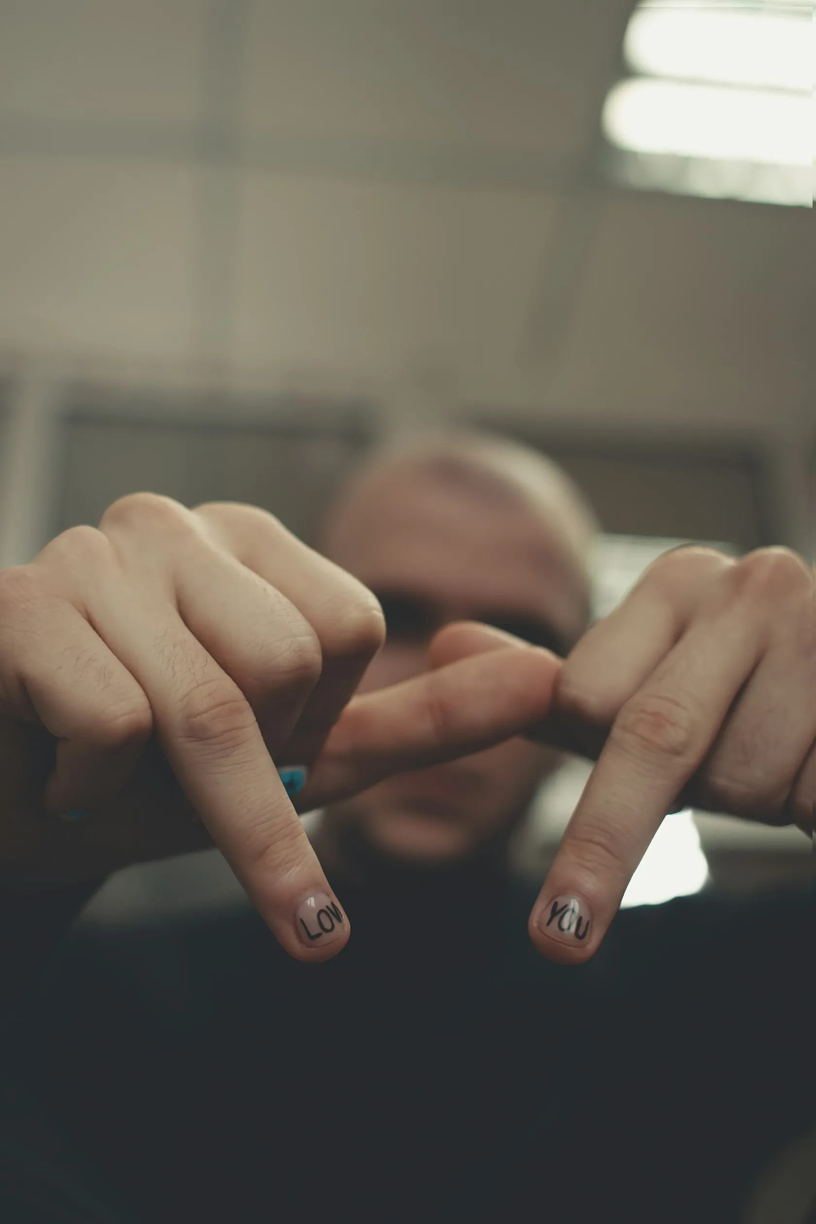 Zwei Hände zeigen die Zeigefinger, auf den Nägeln stehen in schwarzen Buchstaben die Wörter love und you